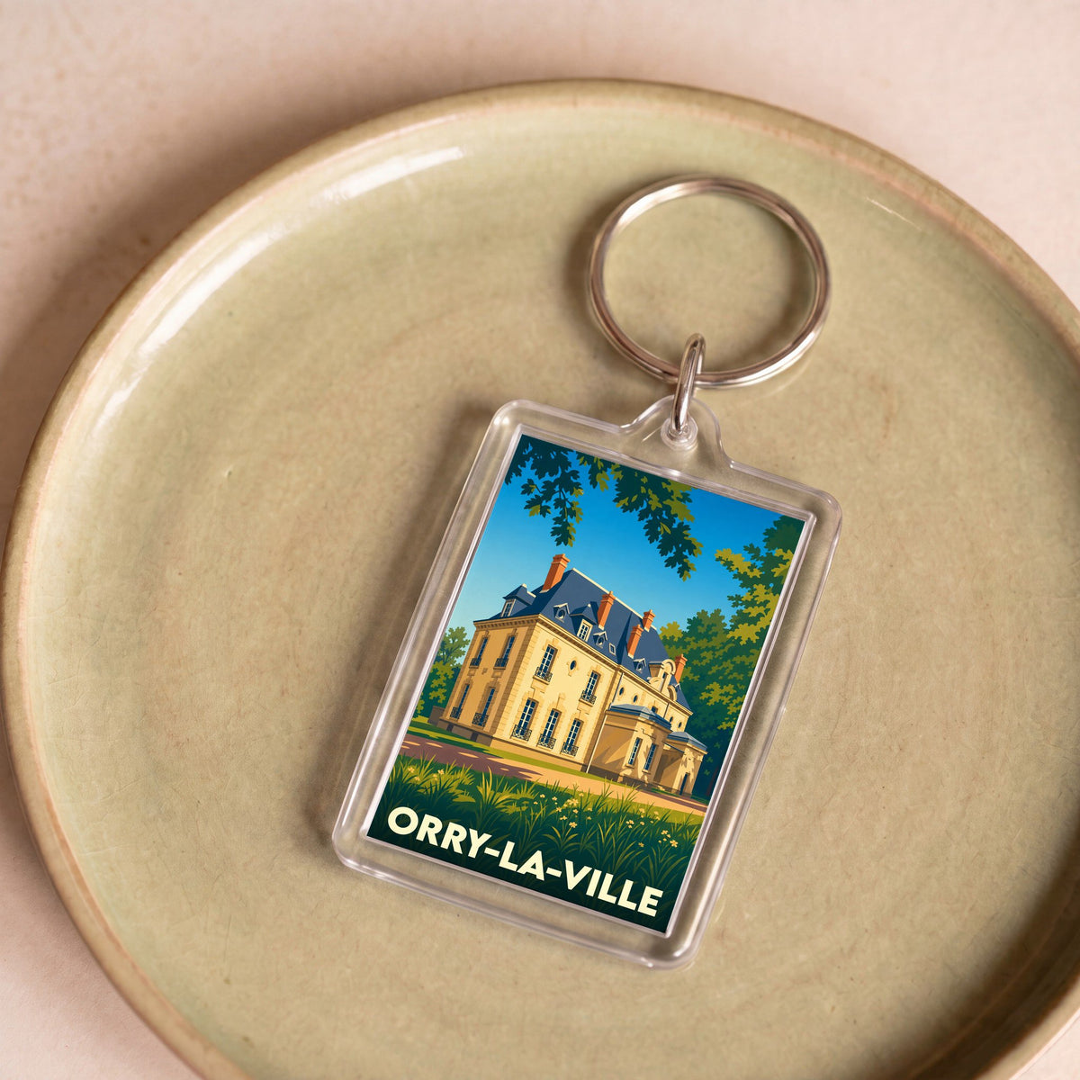 Porte-clés souvenir de la ville de Orry-la-Ville avec une illustration stylisée d'un manoir.