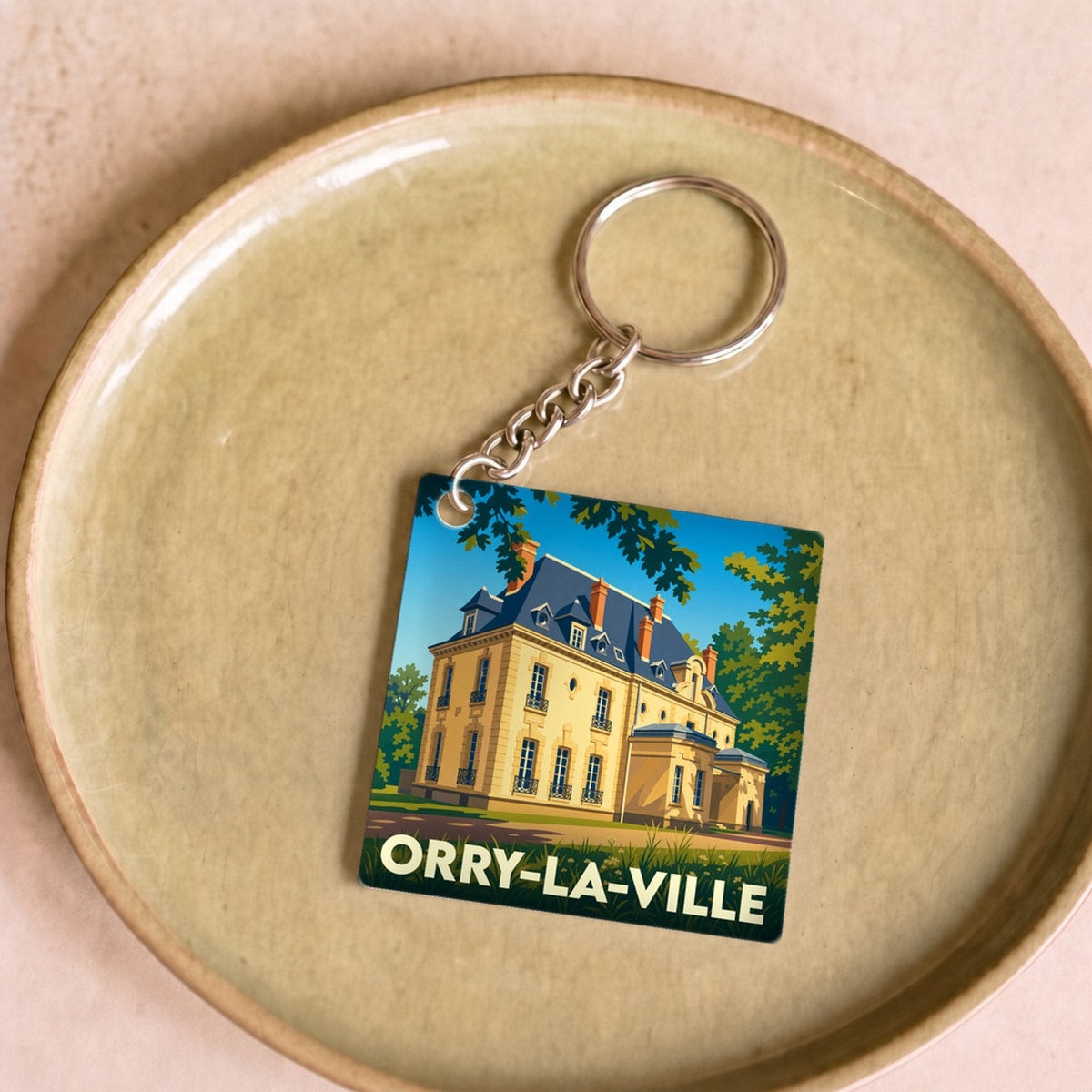 Porte-clés souvenir de la ville de Orry-la-Ville avec une illustration stylisée d'un manoir.
