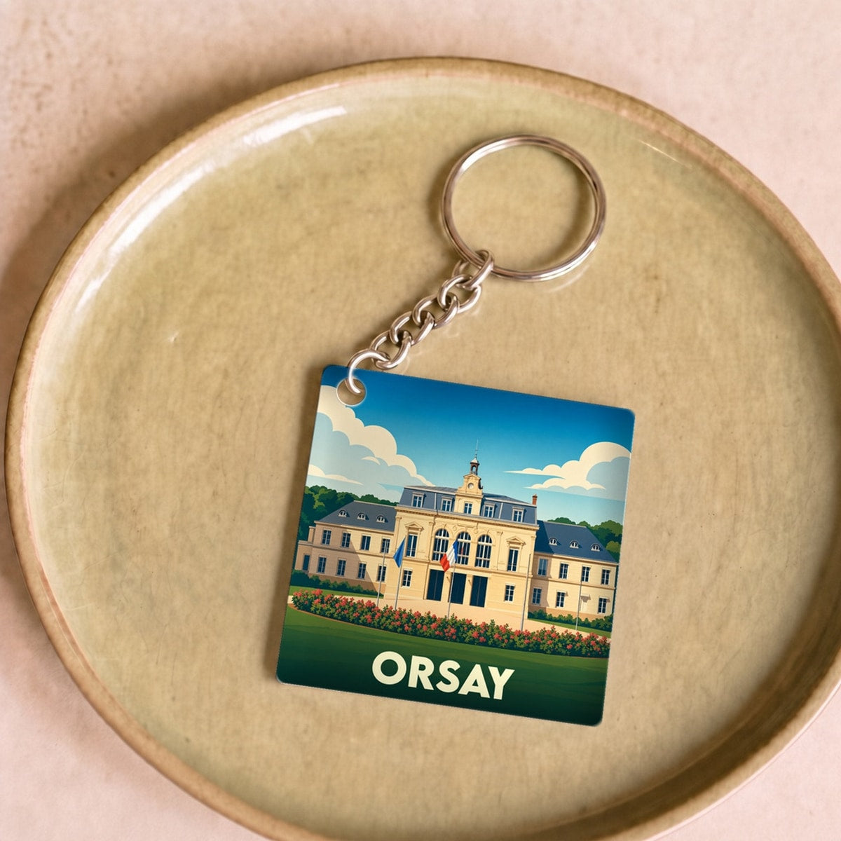 Porte-clés souvenir de la ville de Orsay avec une illustration stylisée d'un bâtiment historique.