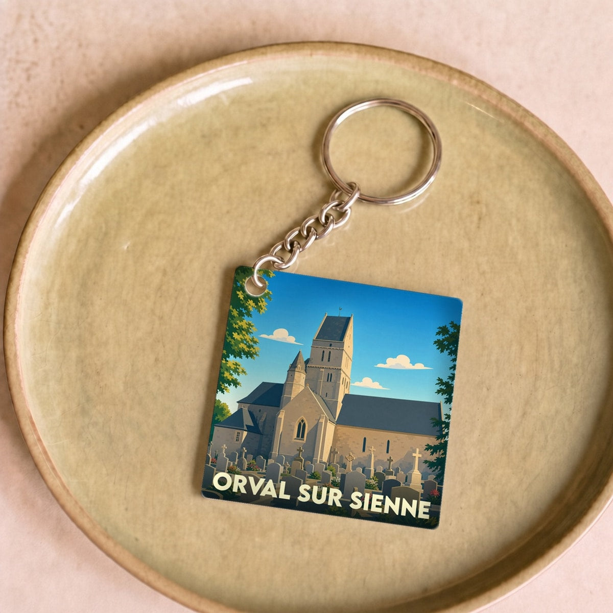 Porte-clés souvenir de la ville d’Orval-sur-Sienne avec une illustration stylisée de son église et de son cimetière.
