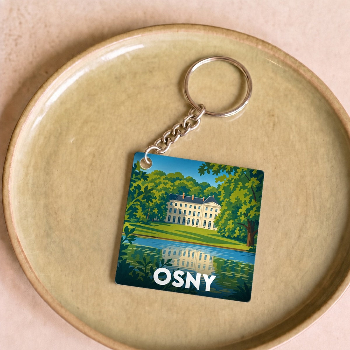 Porte-clés souvenir de la ville d'Osny avec une illustration stylisée d'un château au bord de l'eau.