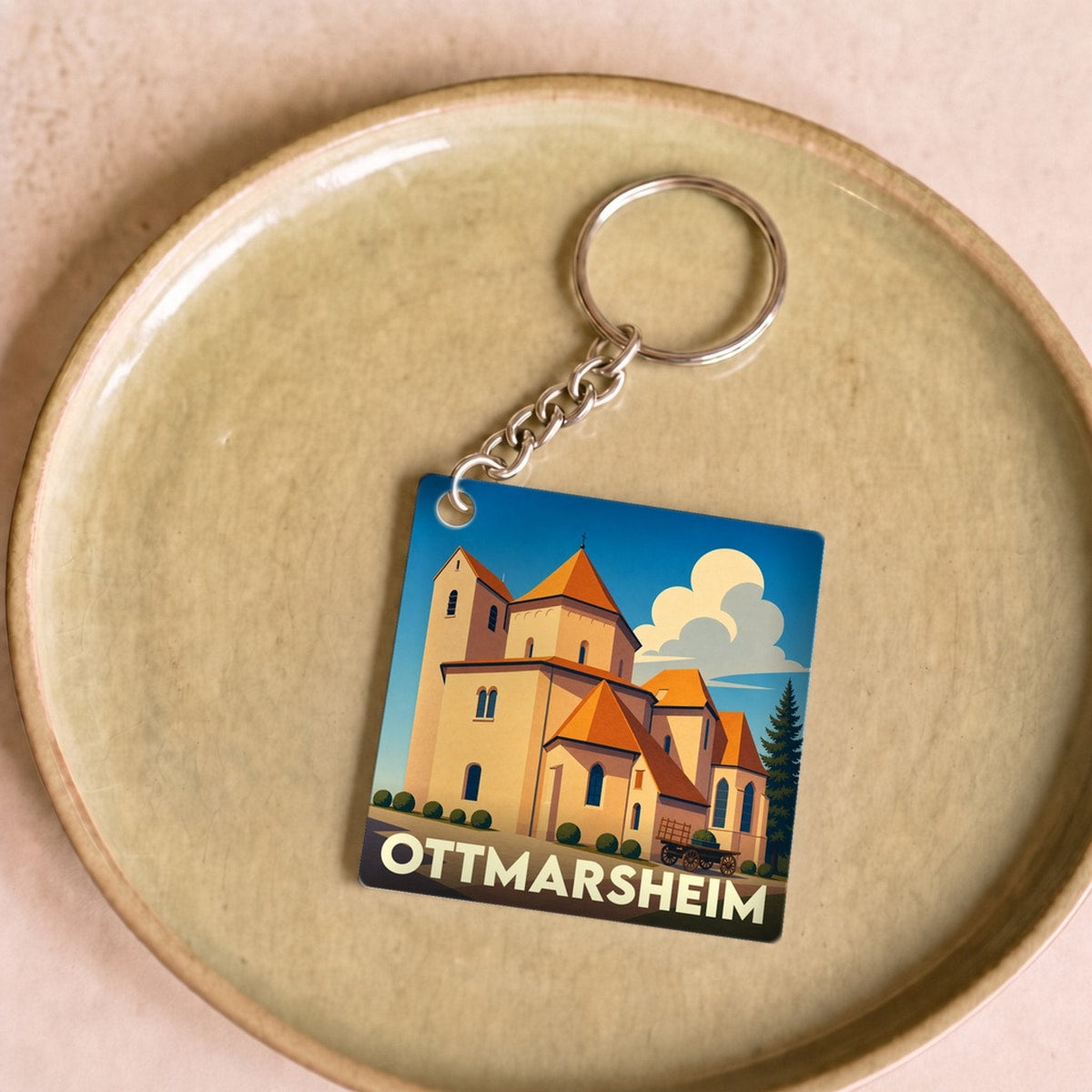 Porte-clés souvenir de la ville d'Ottmarsheim avec une illustration stylisée de son église abbatiale.