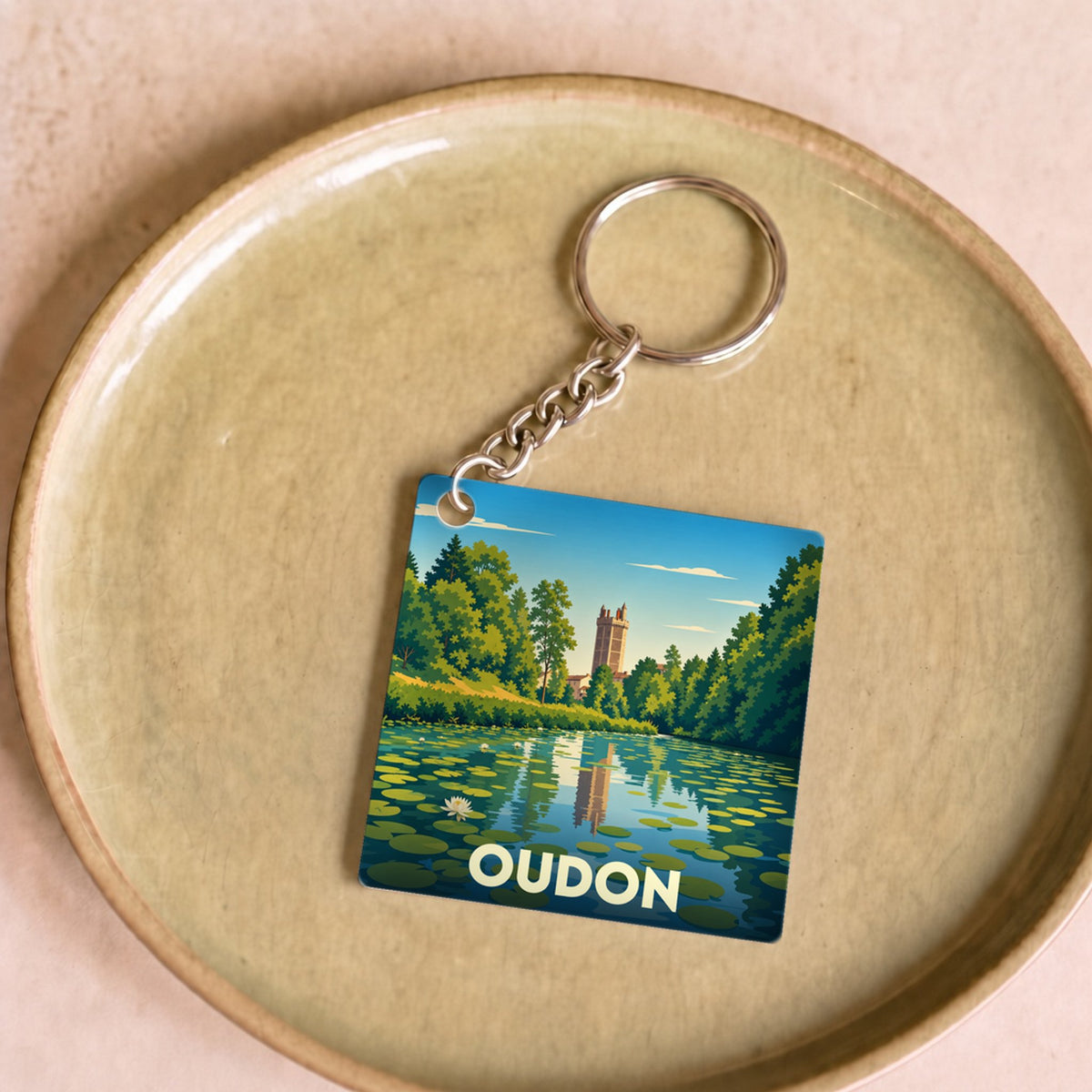 Porte-clés souvenir de la ville de Oudon avec une illustration stylisée d'un étang et son château.
