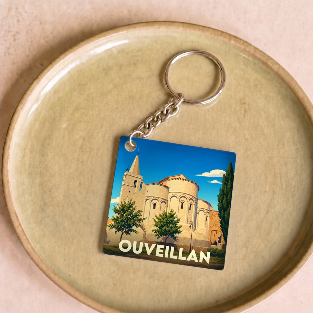 Porte-clés souvenir de la ville d'Ouveillan avec une illustration stylisée de son église.