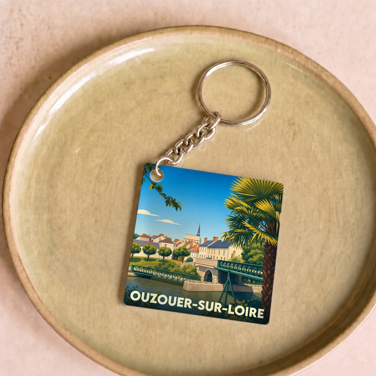 Porte-clés souvenir de la ville de Ouzouer-sur-Loire avec une illustration stylisée.