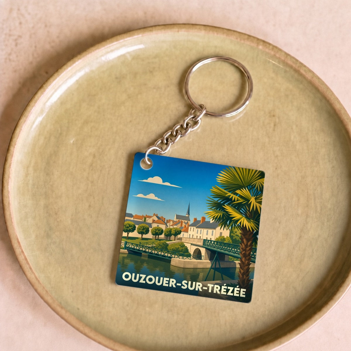 Porte-clés souvenir de la ville d'Ouzouer-sur-Trézée avec une illustration stylisée.