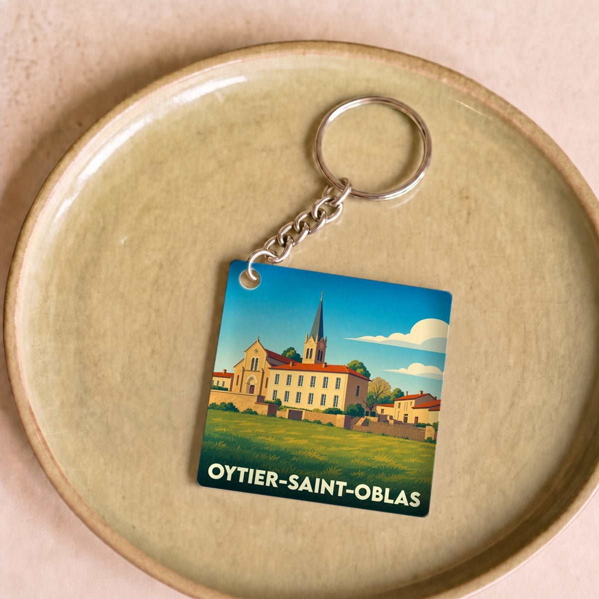 Porte-clés souvenir de la ville de Oytier-Saint-Oblas avec une illustration stylisée d'un paysage urbain.