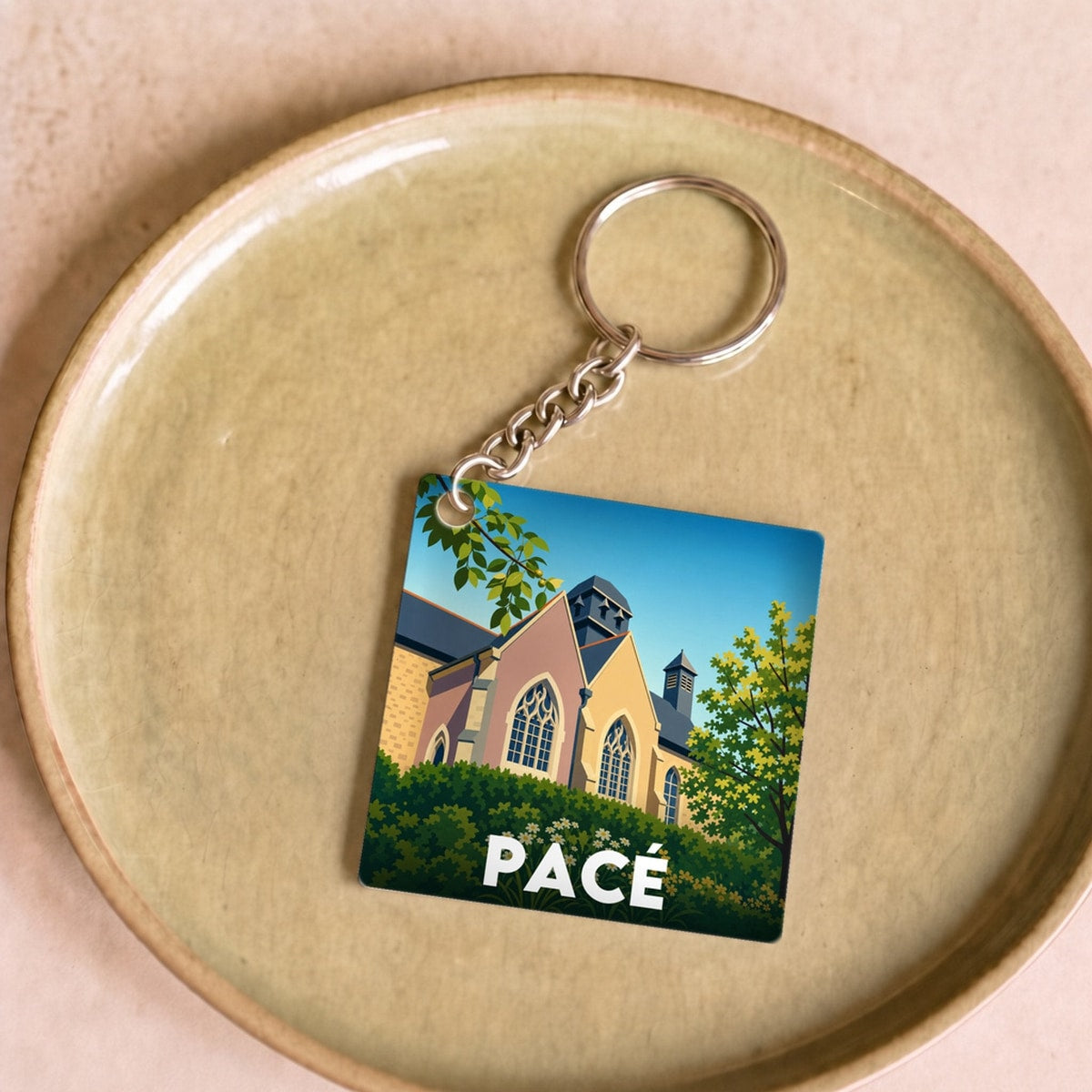 Porte-clés souvenir de la ville de Pacé avec une illustration stylisée.