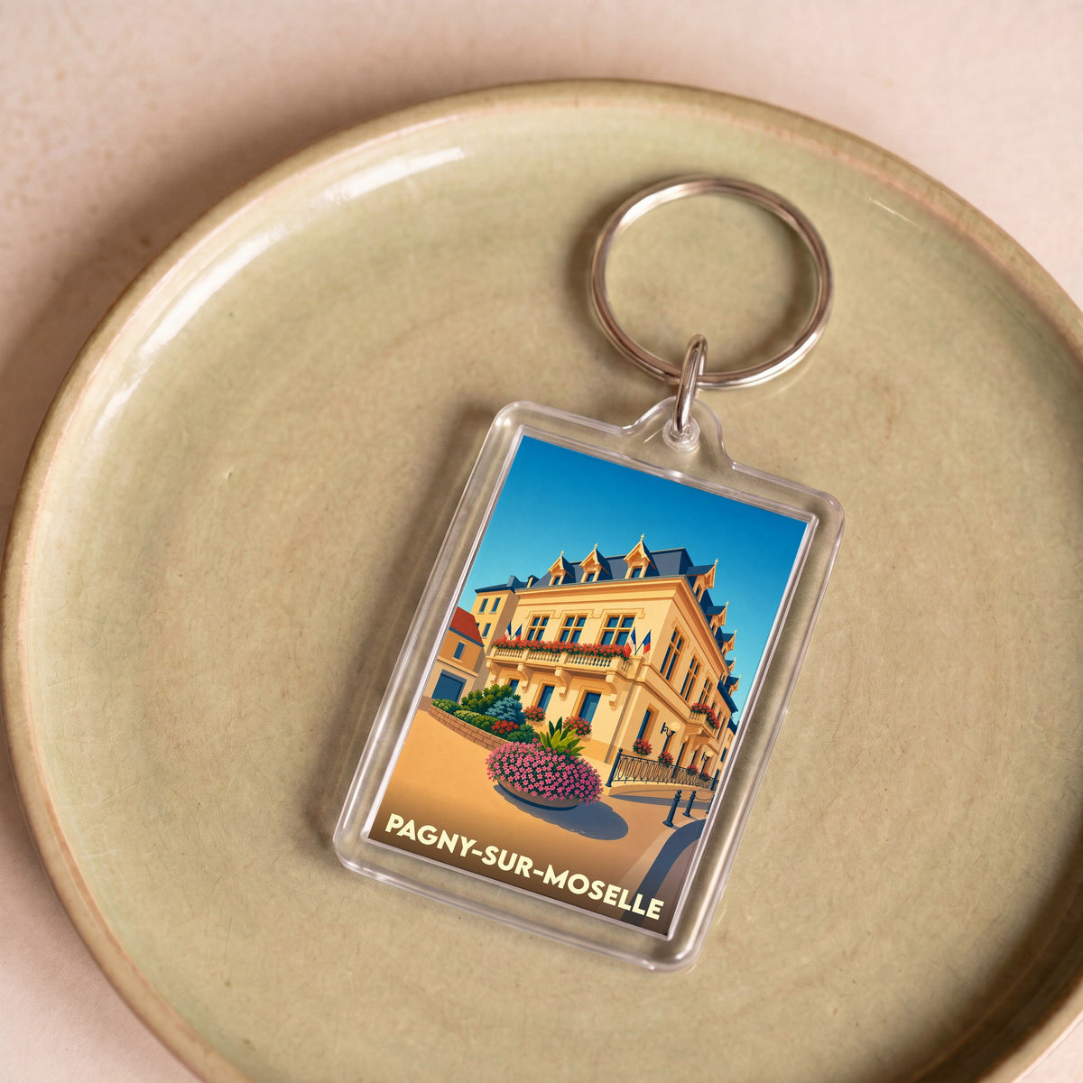 Porte-clés souvenir de la ville de Pagny-sur-Moselle avec une illustration stylisée de son hôtel de ville.