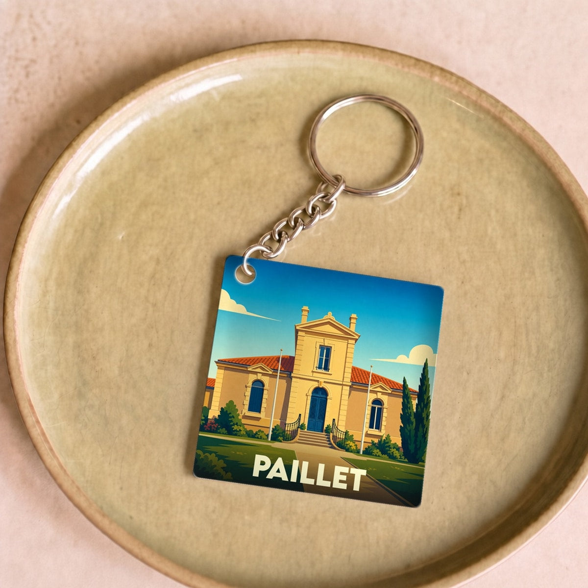 Porte-clés souvenir de la ville de Paillet avec une illustration stylisée.