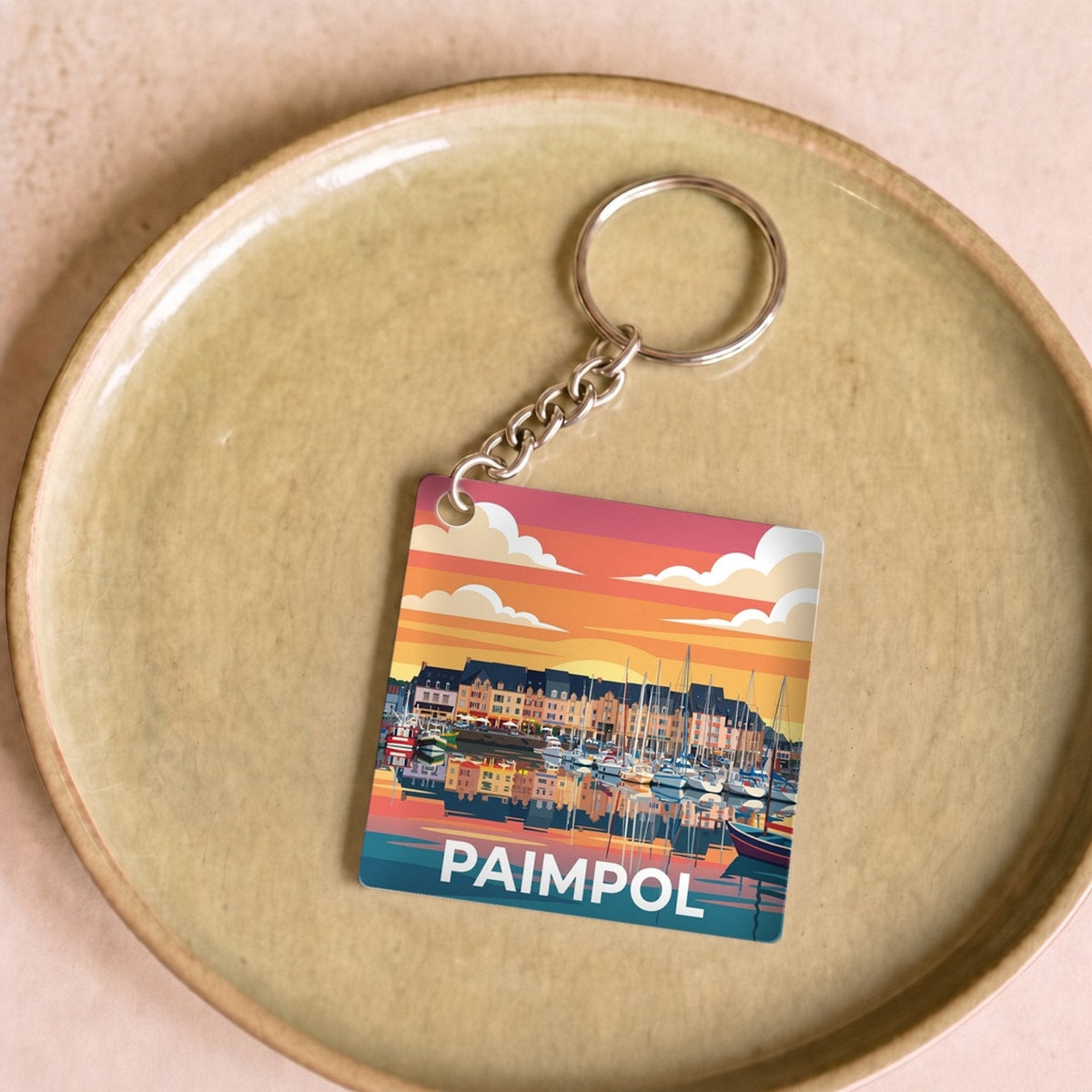 Porte-clés souvenir de la ville de Paimpol avec une illustration stylisée de son port au coucher du soleil.