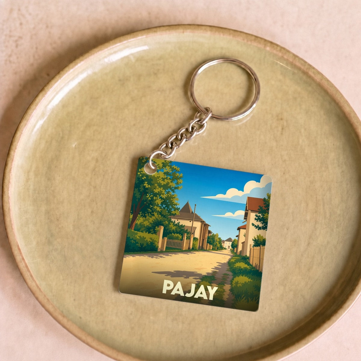 Porte-clés souvenir de la ville de Pajay avec une illustration stylisée d'une rue ensoleillée.