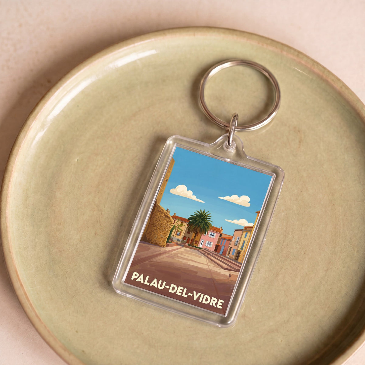 Porte-clés souvenir de la ville de Palau-del-Vidre avec une illustration stylisée.