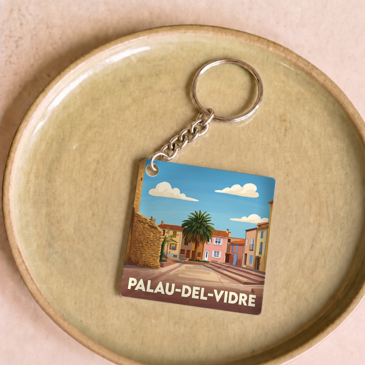 Porte-clés souvenir de la ville de Palau-del-Vidre avec une illustration stylisée.