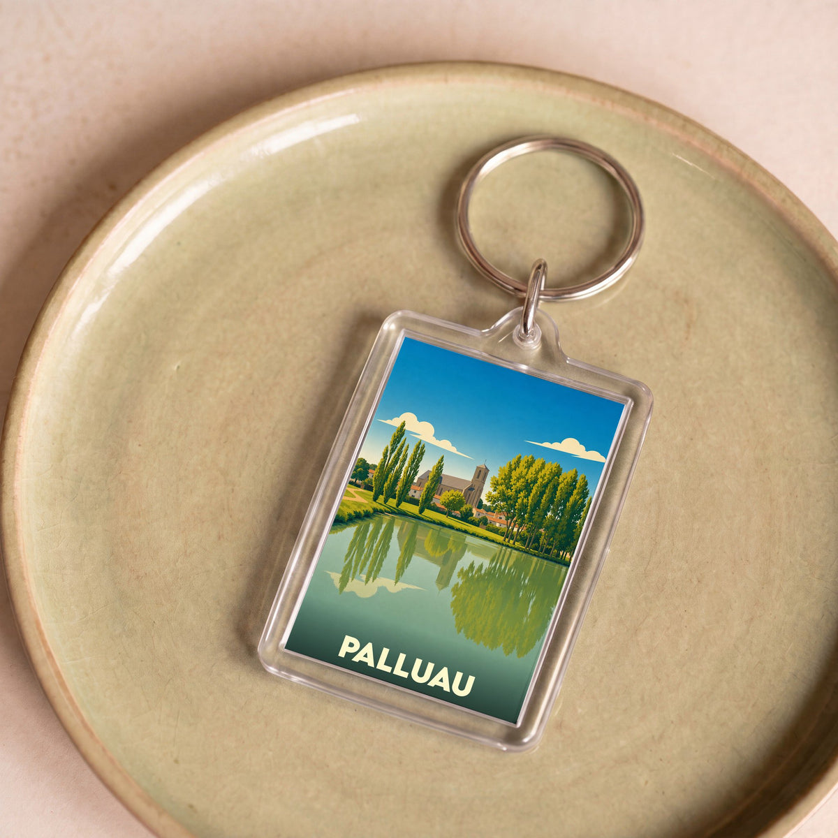 Porte-clés souvenir de la ville de Palluau avec une illustration stylisée d'un paysage aquatique.