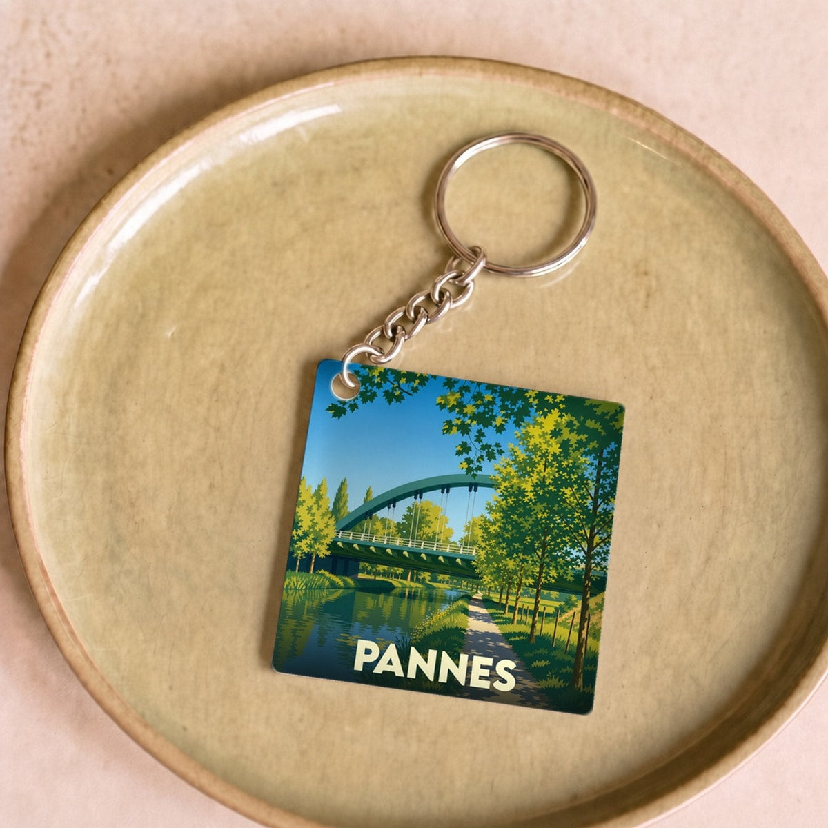 Porte-clés souvenir de la ville de Pannes avec une illustration stylisée d'un pont au-dessus de l'eau.