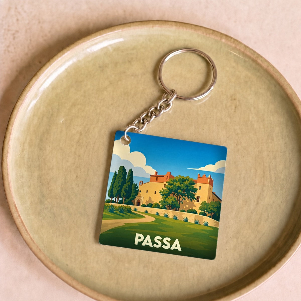 Porte-clés souvenir de la ville de Passa avec une illustration stylisée d'un paysage ensoleillé.