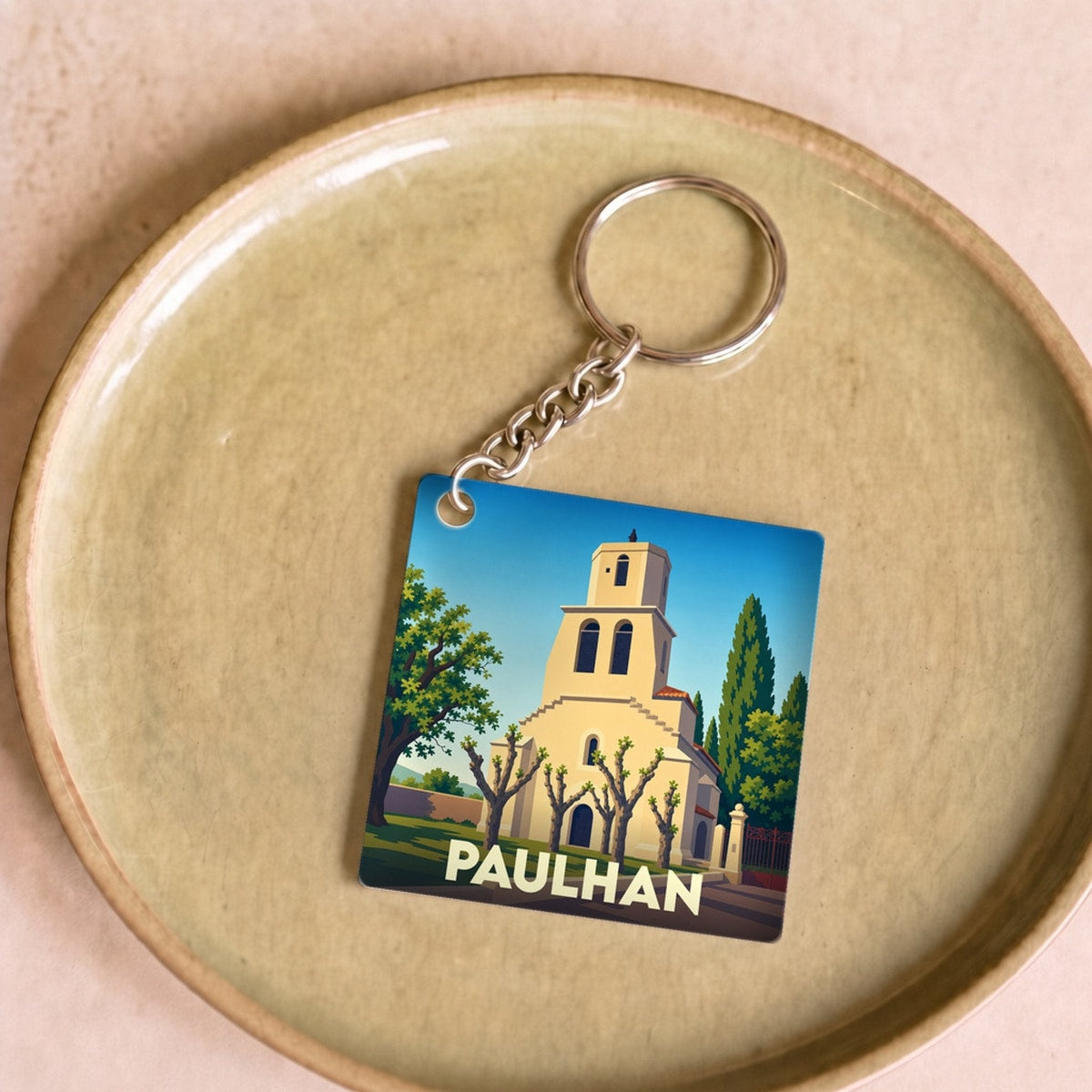 Porte-clés souvenir de la ville de Paulhan avec une illustration stylisée de son église.