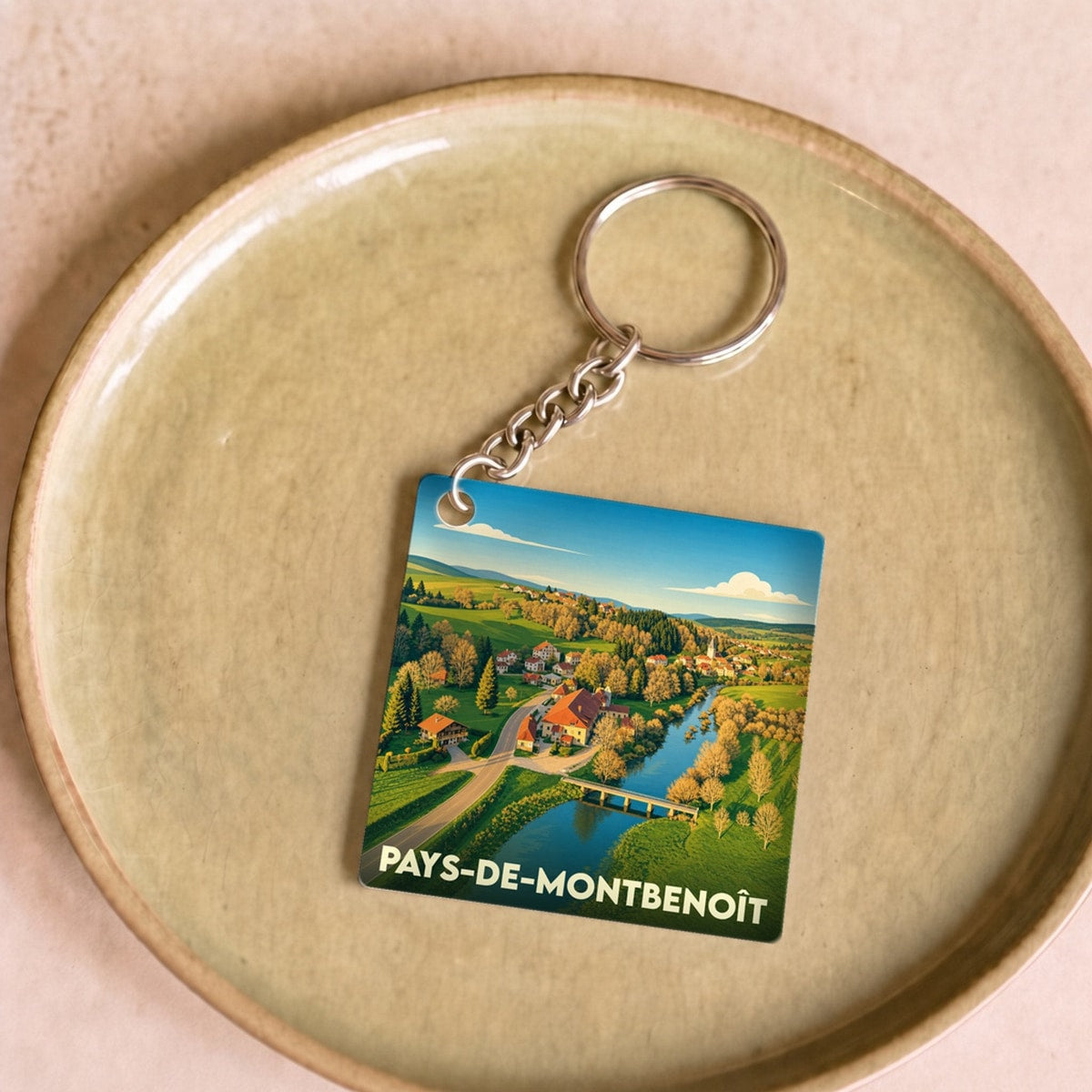 Porte-clés souvenir du Pays-de-Montbenoît avec une illustration stylisée d'un paysage rural.