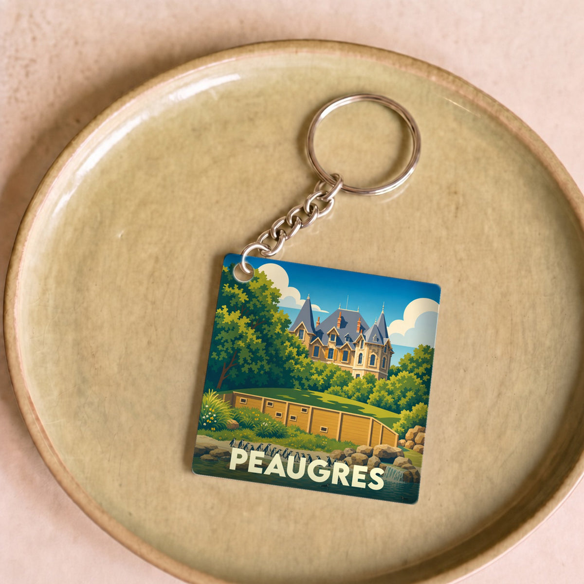 Porte-clés souvenir de la ville de Peaugres avec une illustration stylisée.
