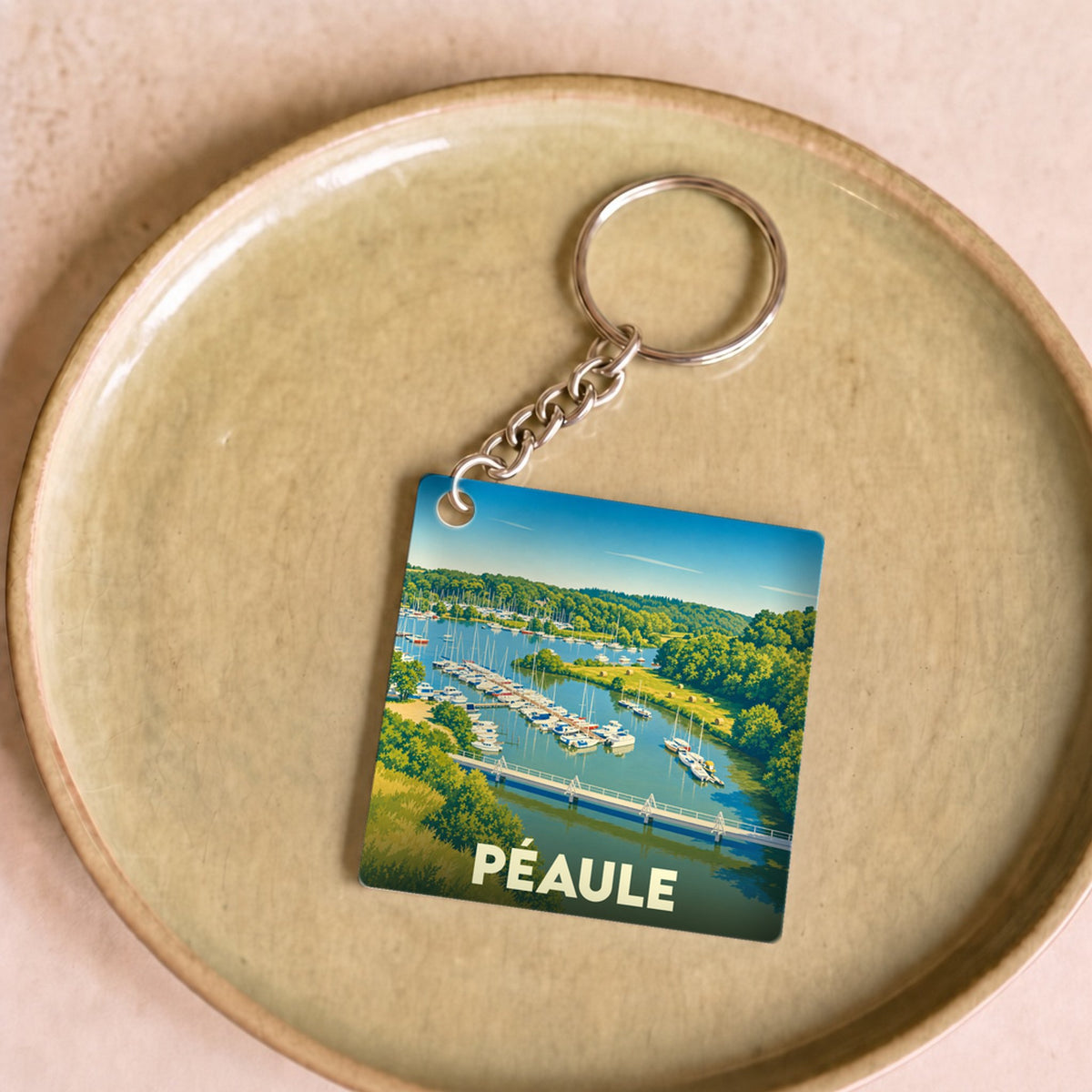 Porte-clés souvenir de la ville de Péaule avec une illustration stylisée d'un port de plaisance.