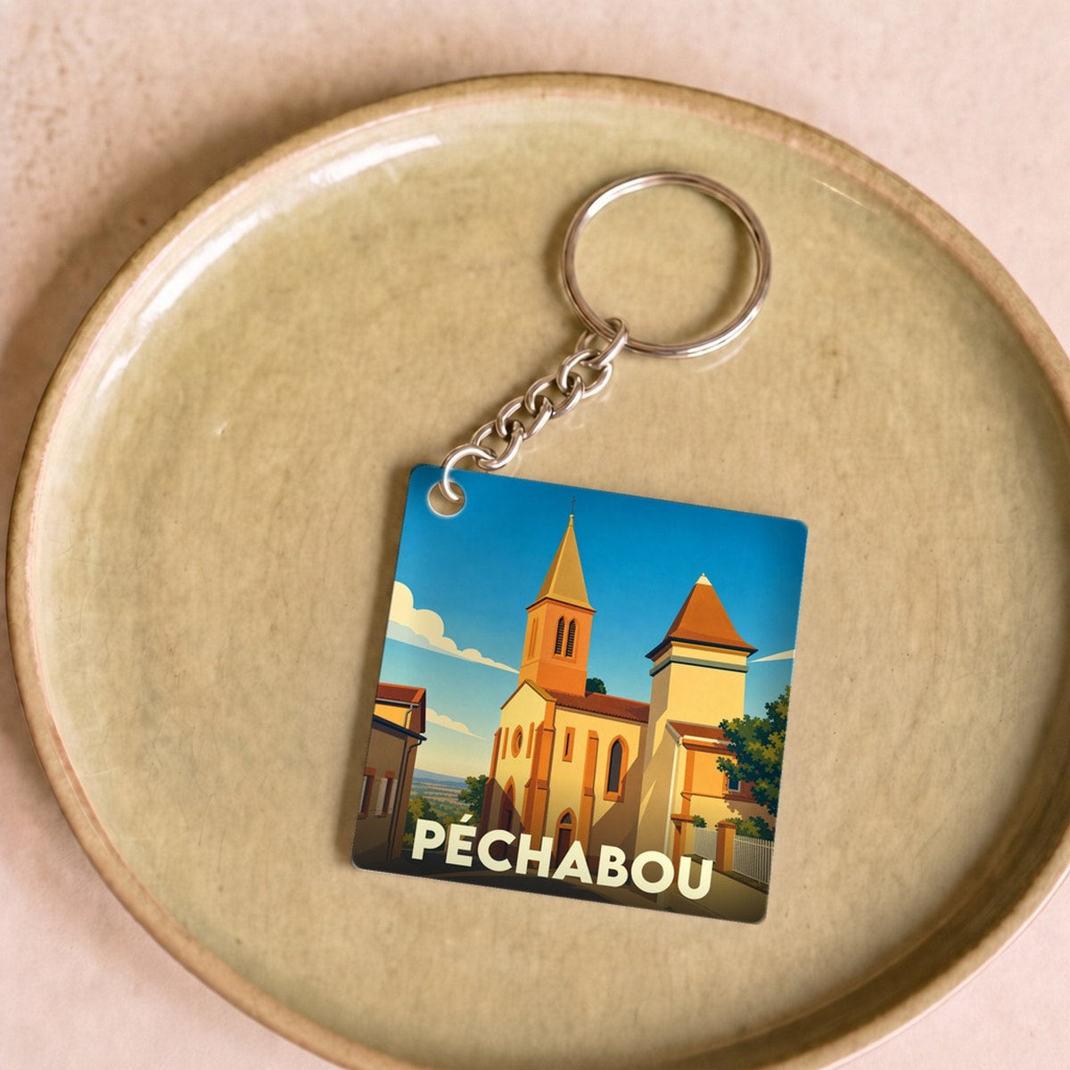 Porte-clés souvenir de la ville de Péchabou avec une illustration stylisée de son église.