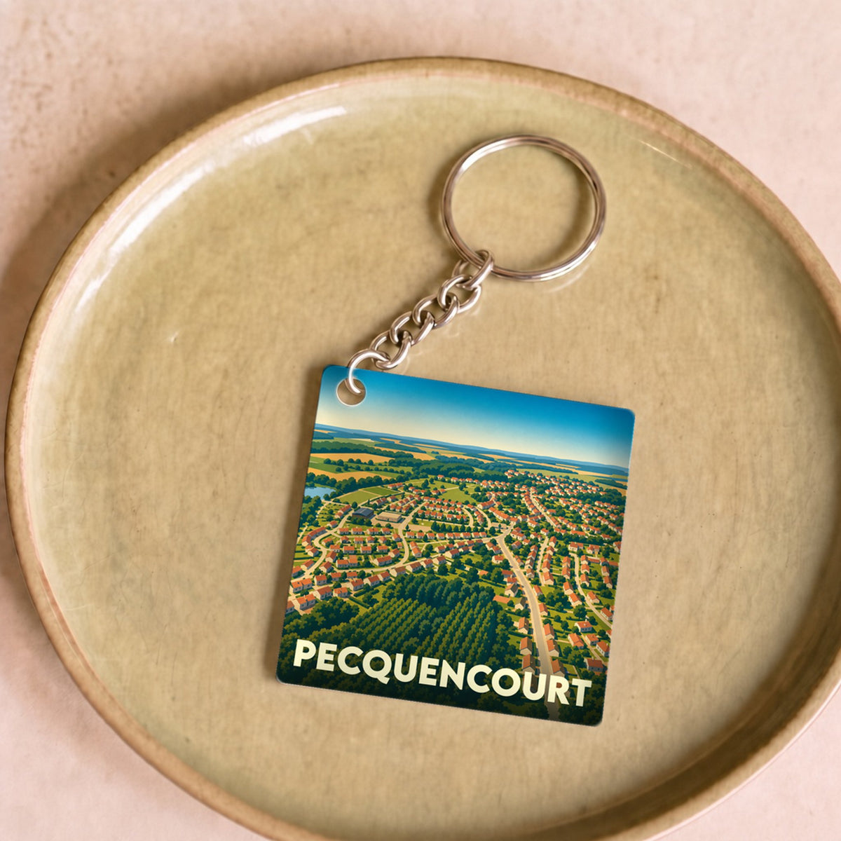Porte-clés souvenir de la ville de Pecquencourt avec une illustration aérienne stylisée.