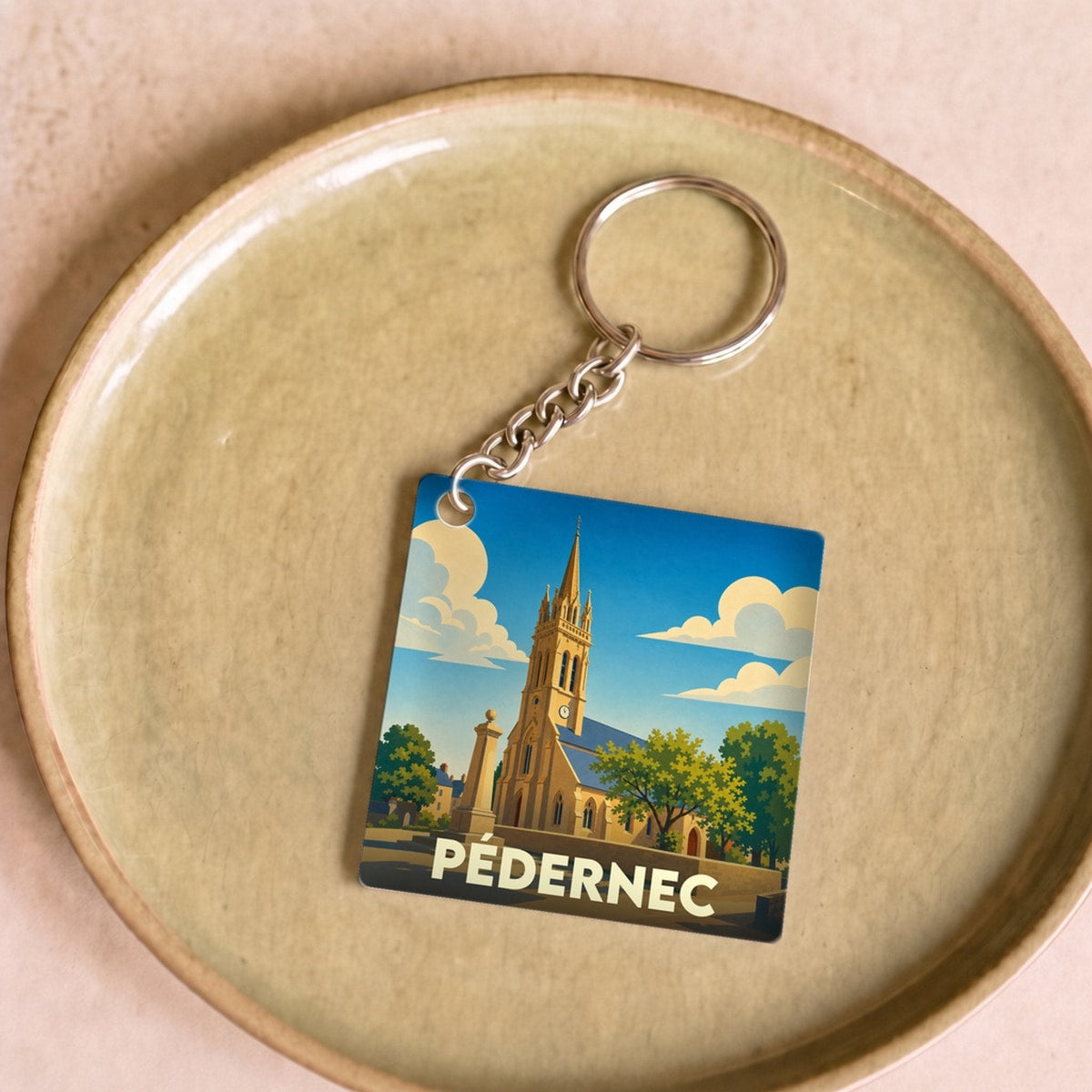 Porte-clés souvenir de la ville de Pédernec avec une illustration stylisée de son église.