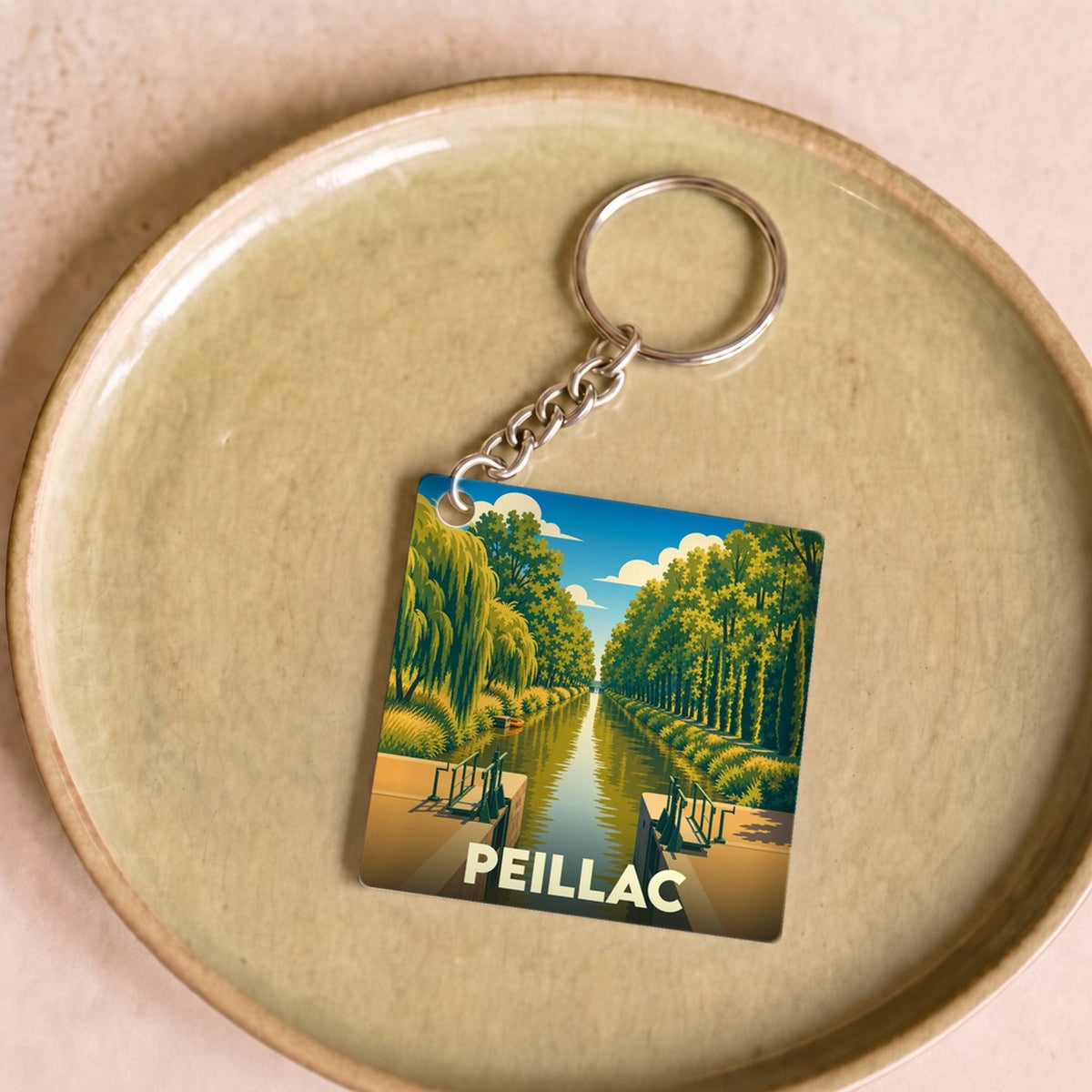 Porte-clés souvenir de la ville de Peillac avec une illustration stylisée d'un canal et d'une écluse.
