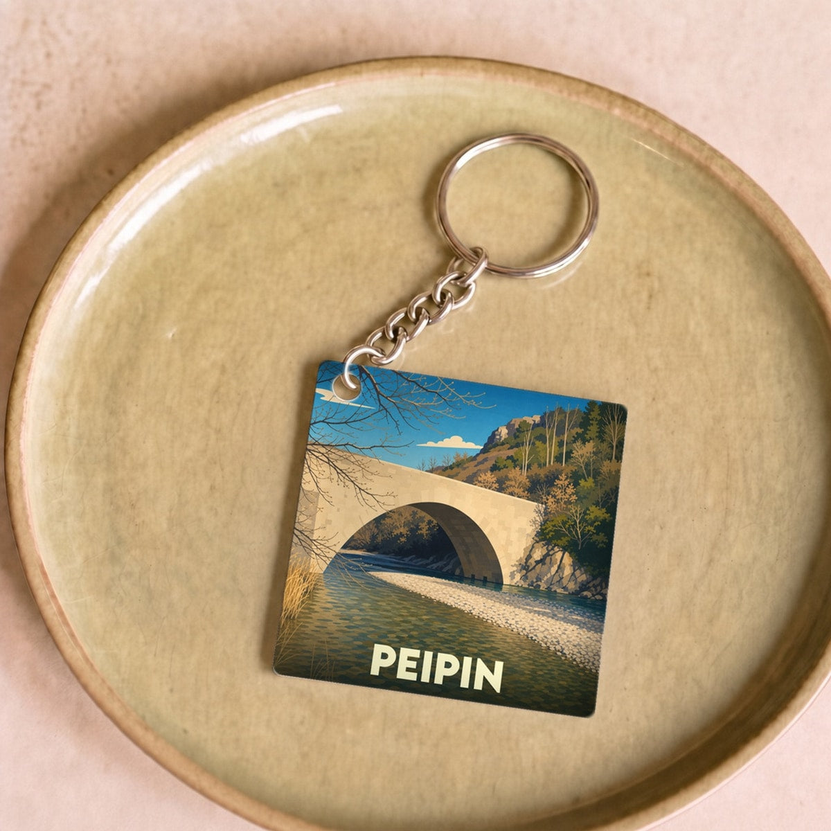 Porte-clés souvenir de la ville de Peipin avec une illustration stylisée de son pont.