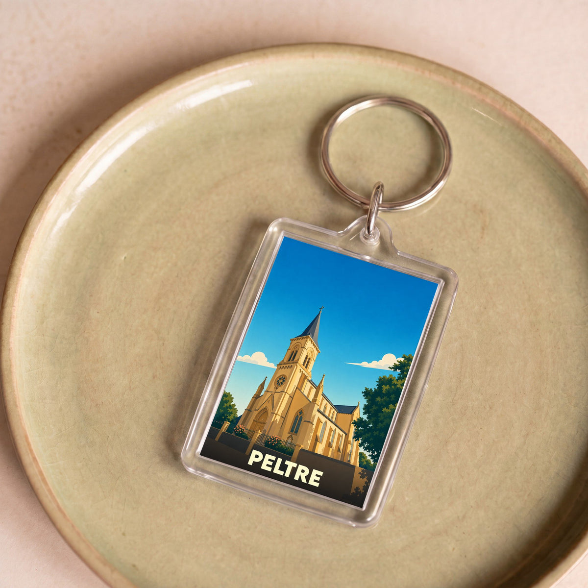 Porte-clés souvenir de la ville de Peltre avec une illustration stylisée de son église.