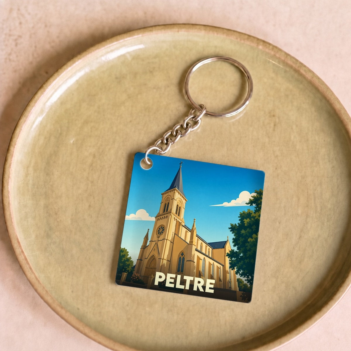 Porte-clés souvenir de la ville de Peltre avec une illustration stylisée de son église.