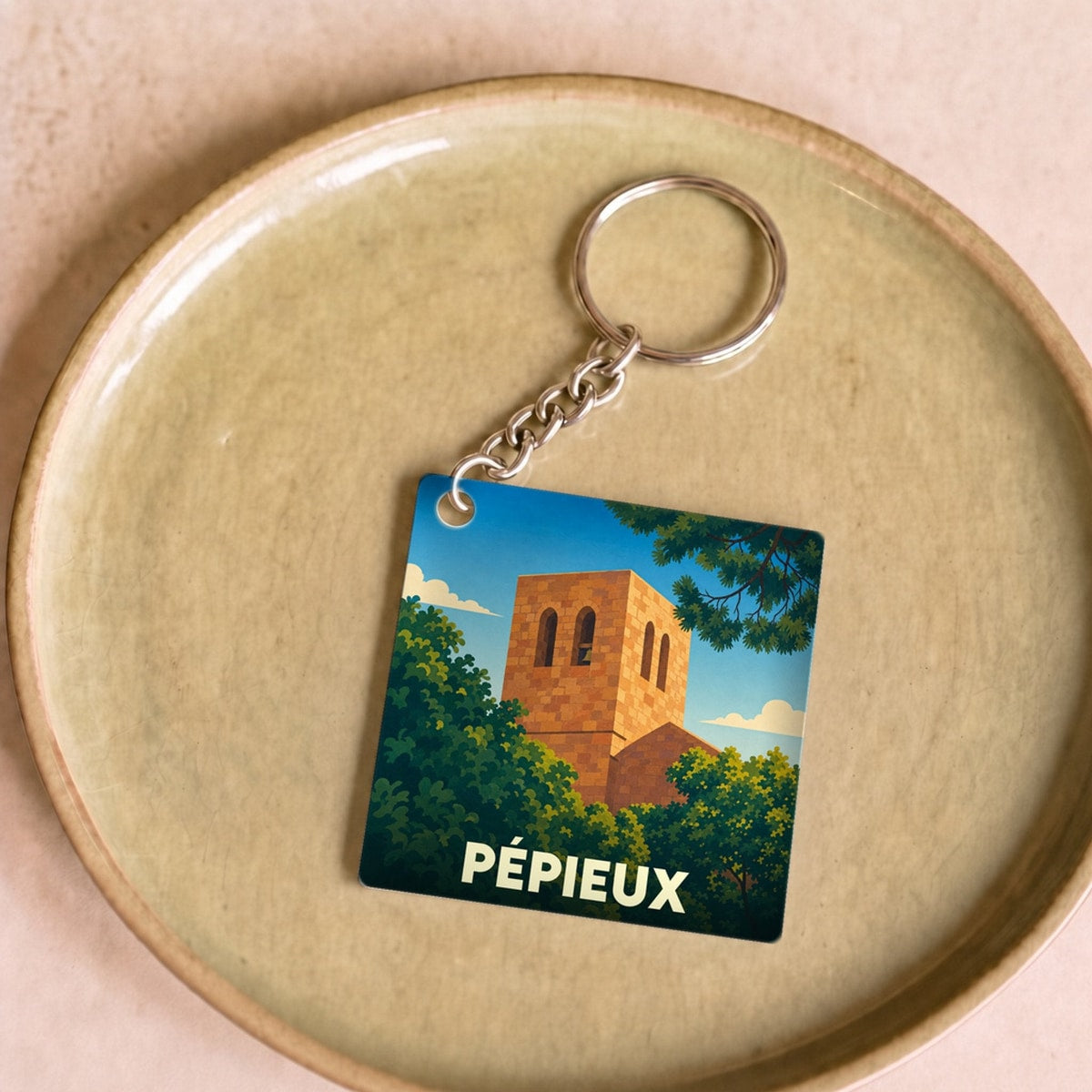 Porte-clés souvenir de la ville de Pépieux avec une illustration stylisée.
