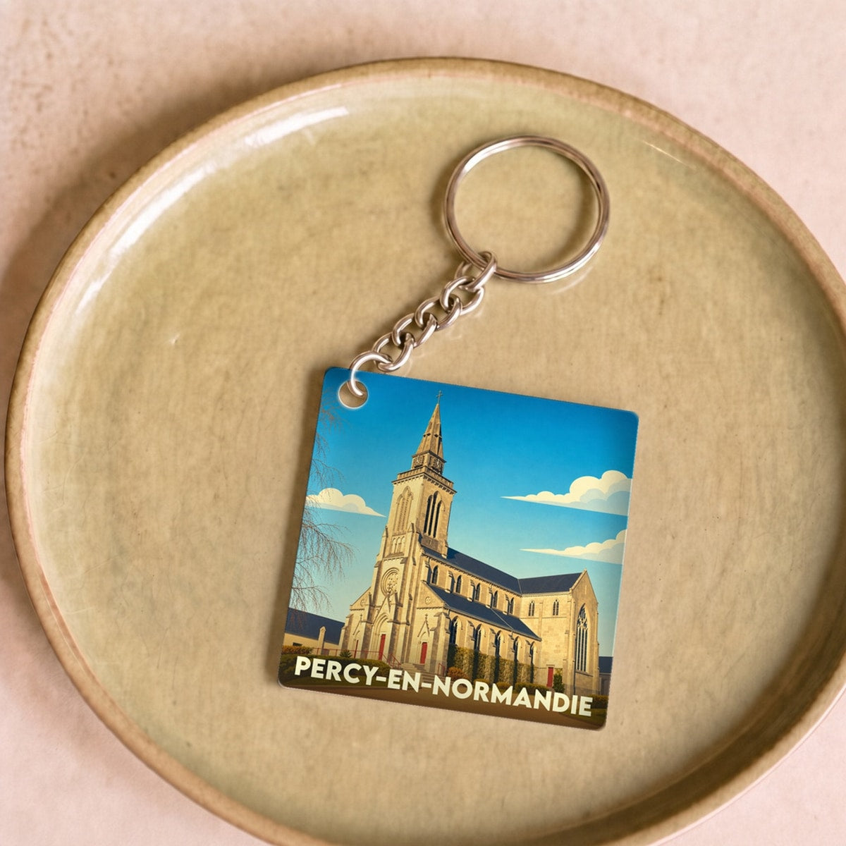Porte-clés souvenir de la ville de Percy-en-Normandie avec une illustration stylisée de son église.