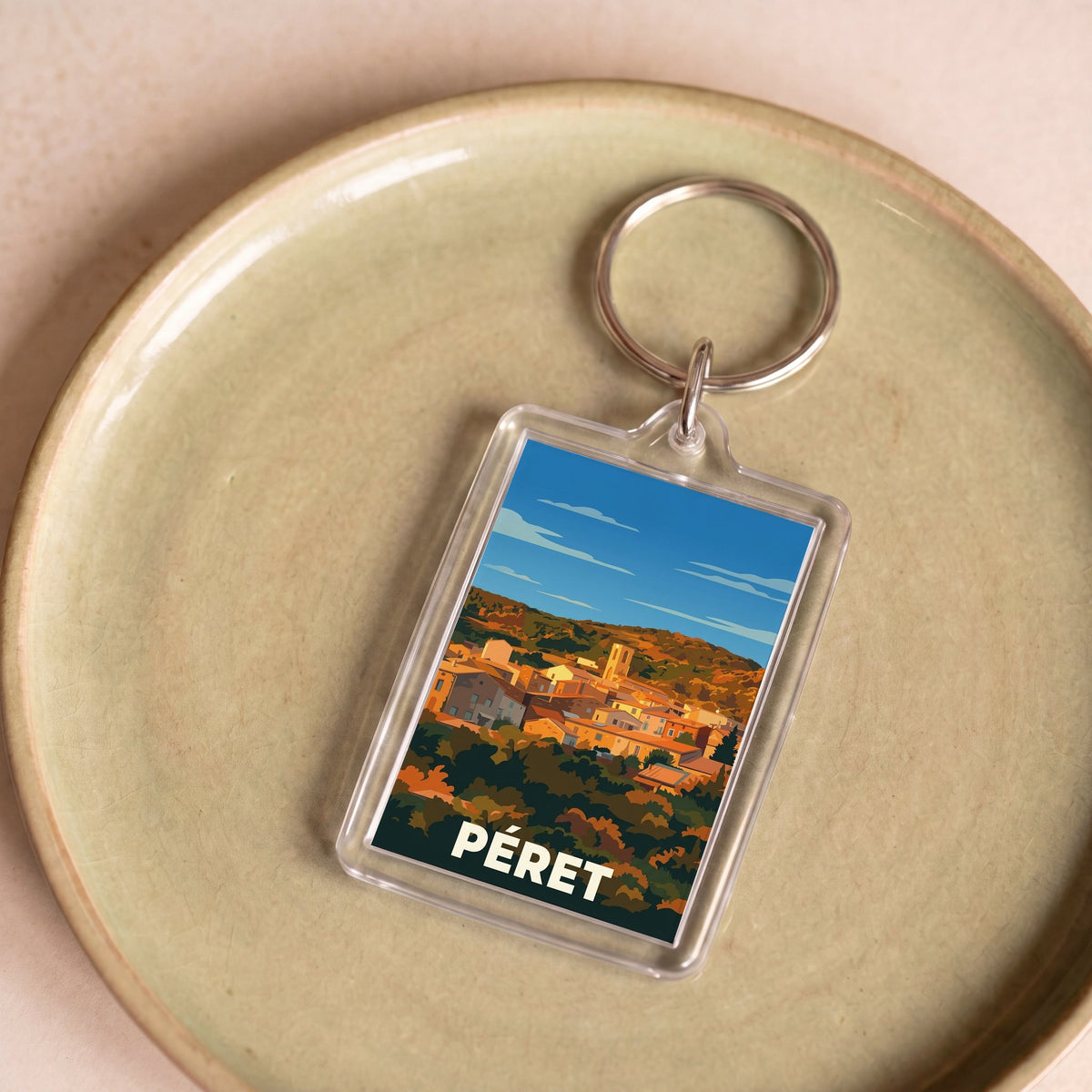 Porte-clés souvenir de la ville de Péret avec une illustration stylisée.