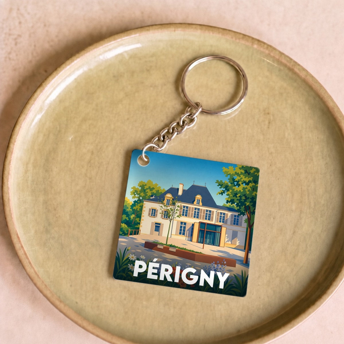 Porte-clés souvenir de la ville de Périgny avec une illustration stylisée d'une demeure historique.