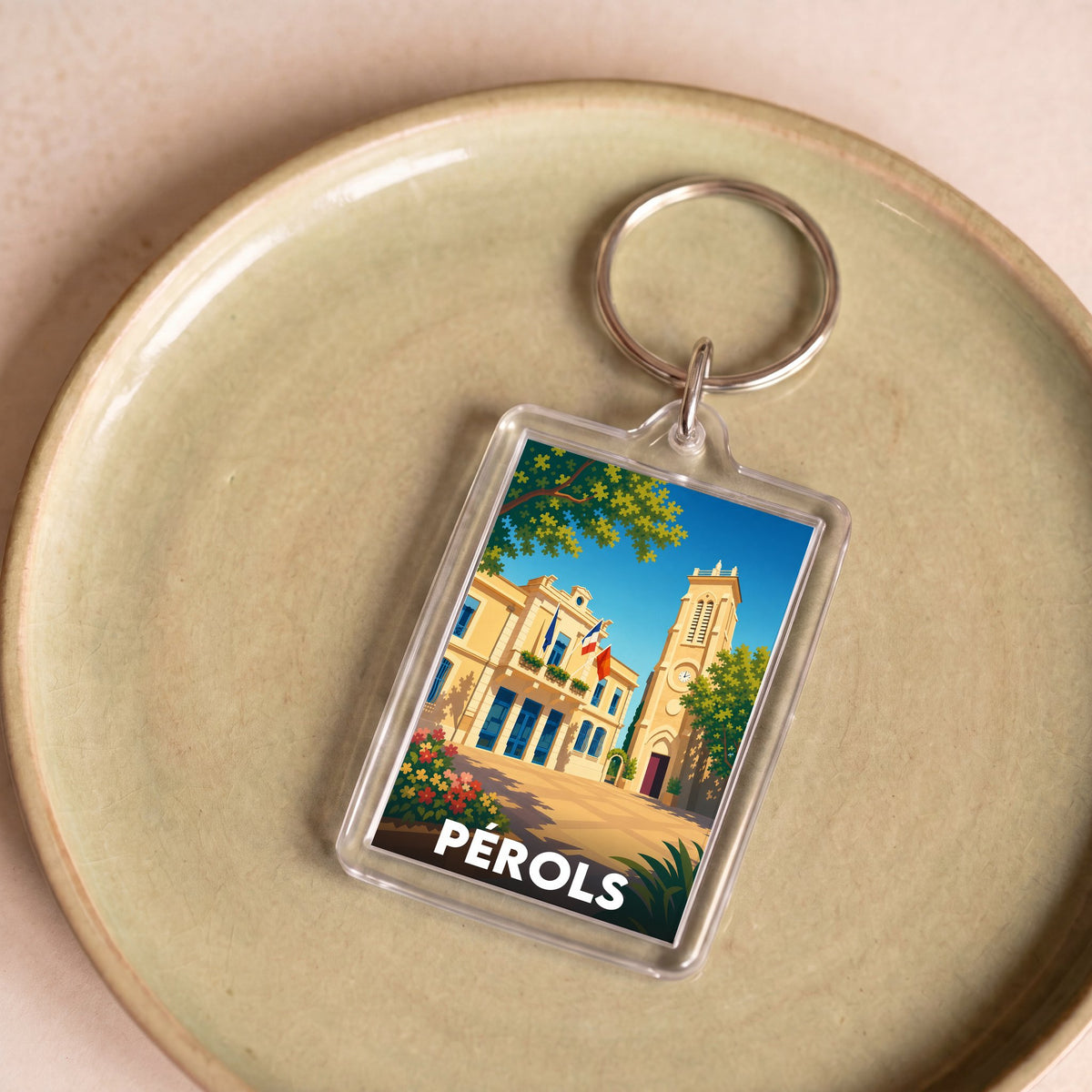 Porte-clés souvenir de la ville de Pérols avec une illustration stylisée de son hôtel de ville.