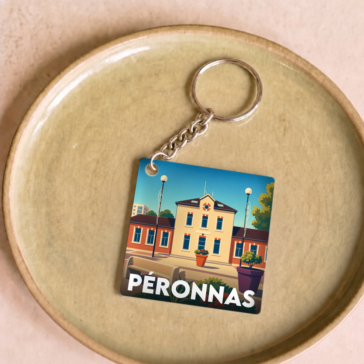 Porte-clés souvenir de la ville de Péronnas avec une illustration stylisée de son architecture.
