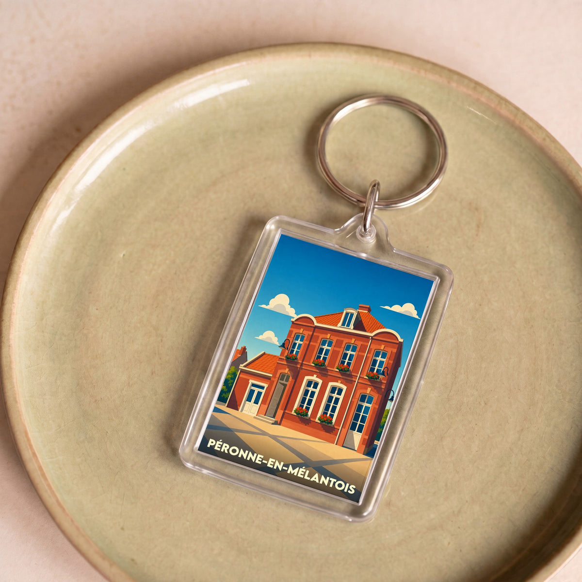 Porte-clés souvenir de la ville de Péronne-en-Mélantois avec une illustration stylisée d'un bâtiment en briques.