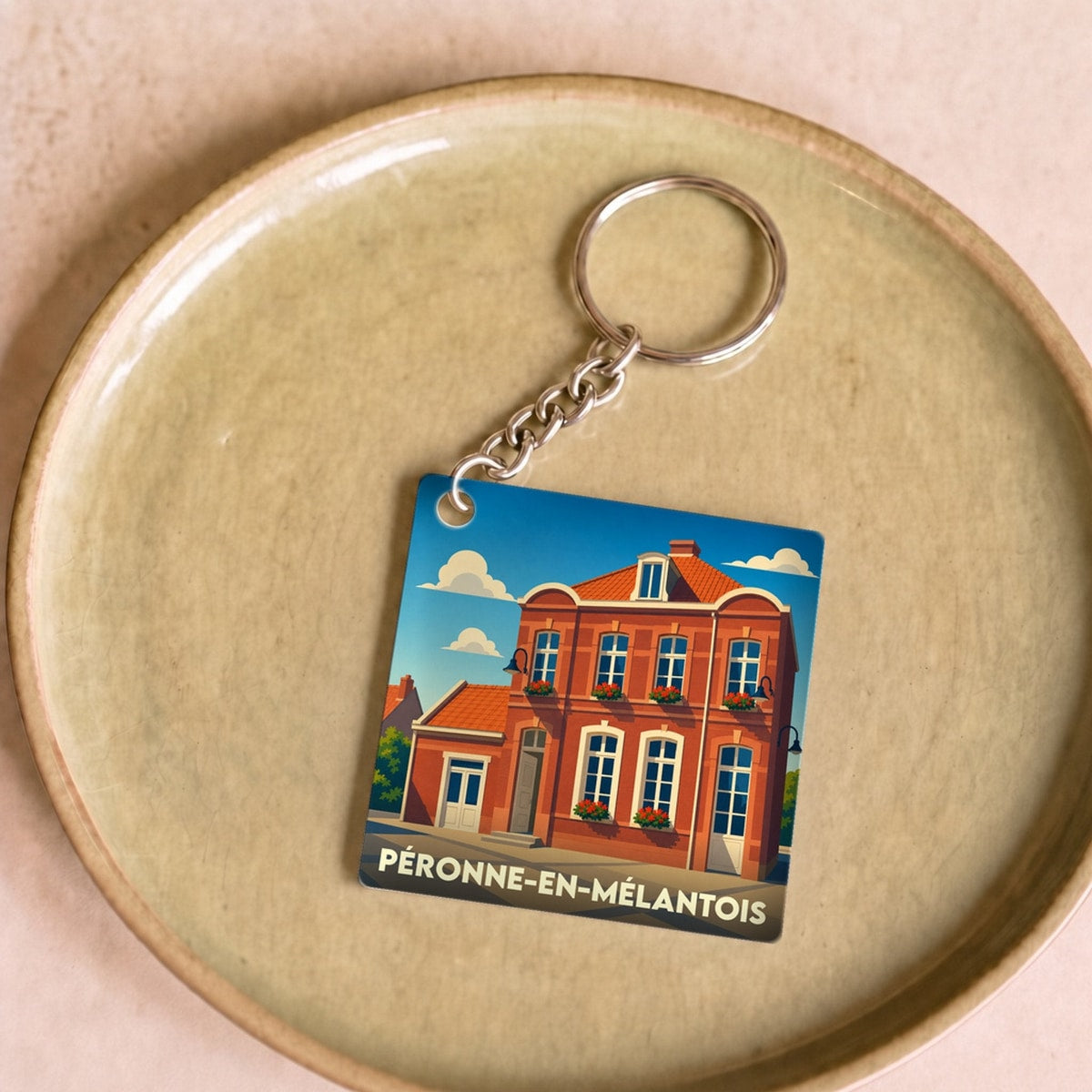 Porte-clés souvenir de la ville de Péronne-en-Mélantois avec une illustration stylisée d'un bâtiment en briques.