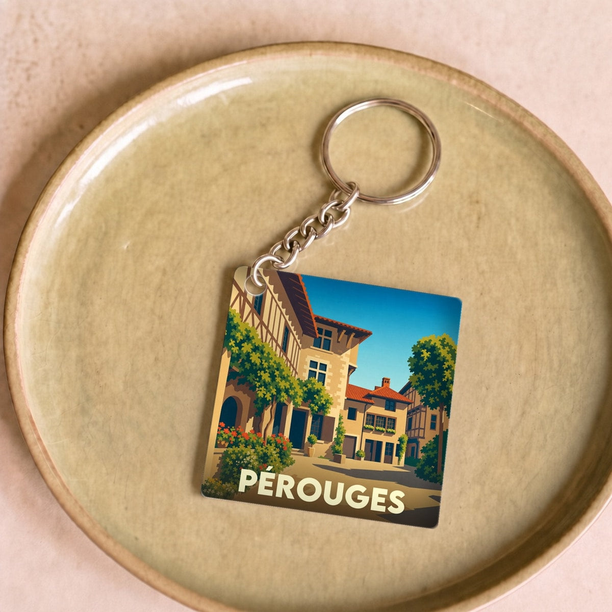 Porte-clés souvenir de la ville de Pérouges avec une illustration stylisée de ses maisons médiévales.