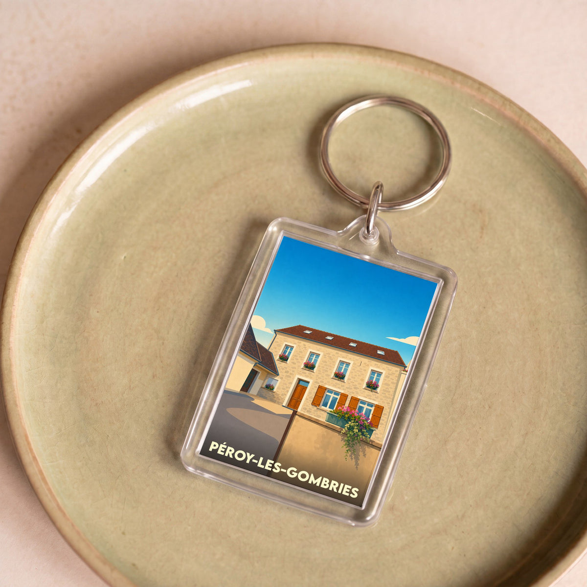 Porte-clés souvenir de la ville de Péroy-les-Gombries avec une illustration stylisée d'une maison fleurie.