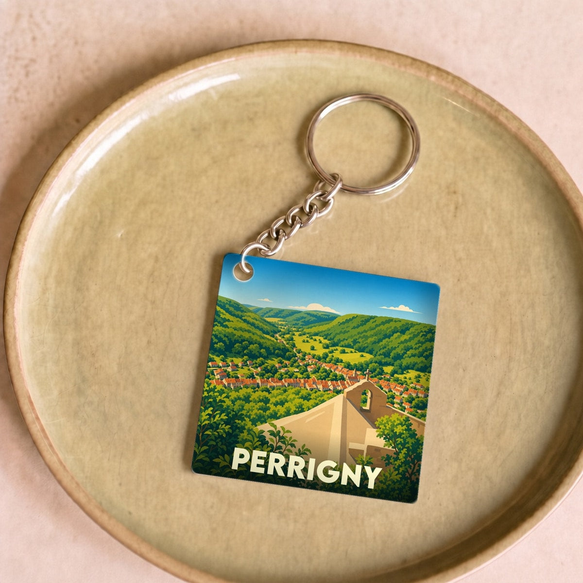 Porte-clés souvenir de la ville de Perrigny avec une illustration stylisée d'un paysage de vallée.