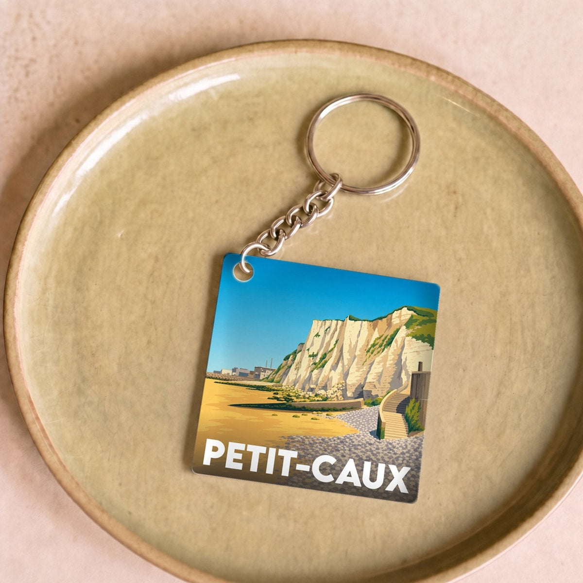 Porte-clés souvenir de la ville de Petit-Caux avec une illustration stylisée des falaises.