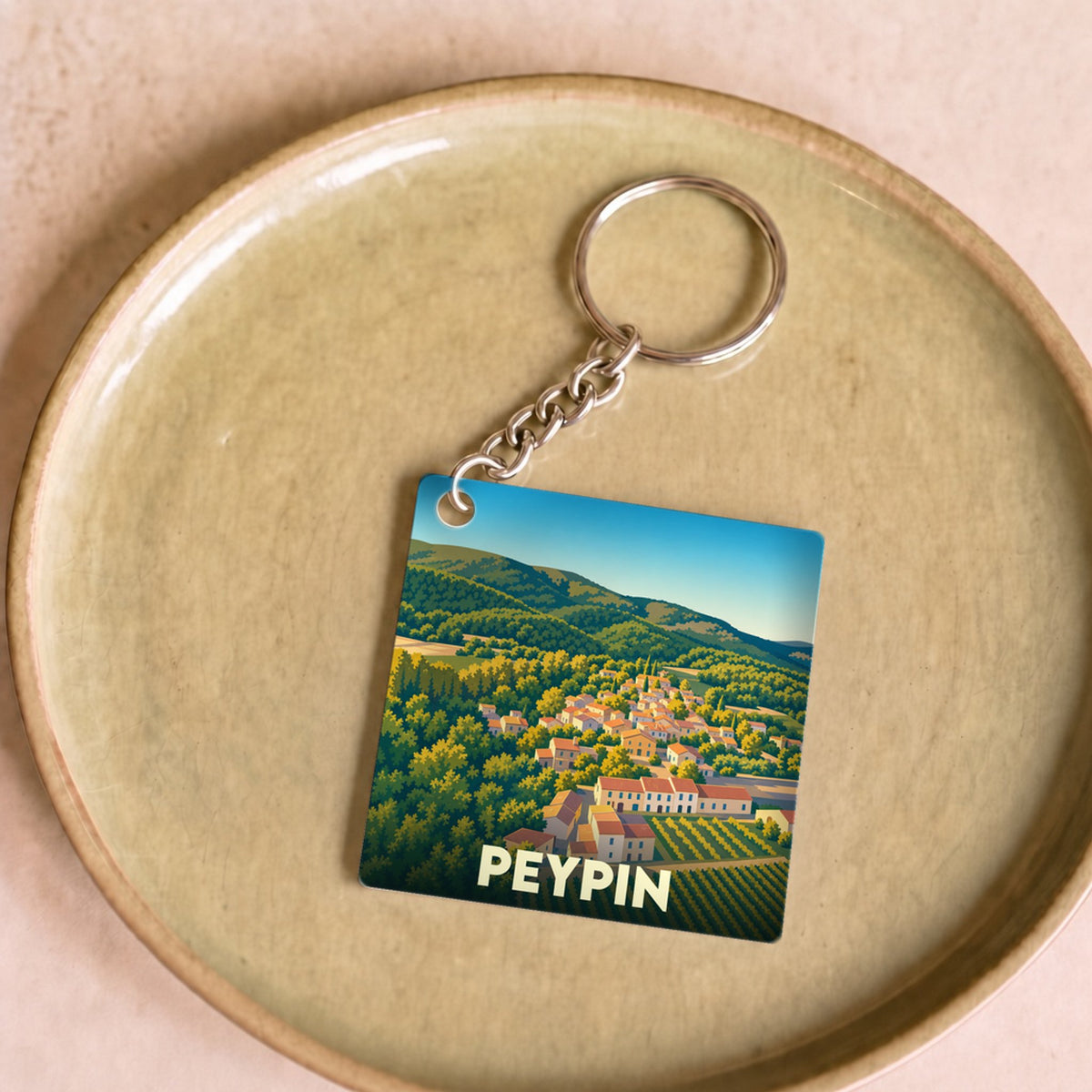 Porte-clés souvenir de la ville de Peypin avec une illustration stylisée d'un paysage provençal.