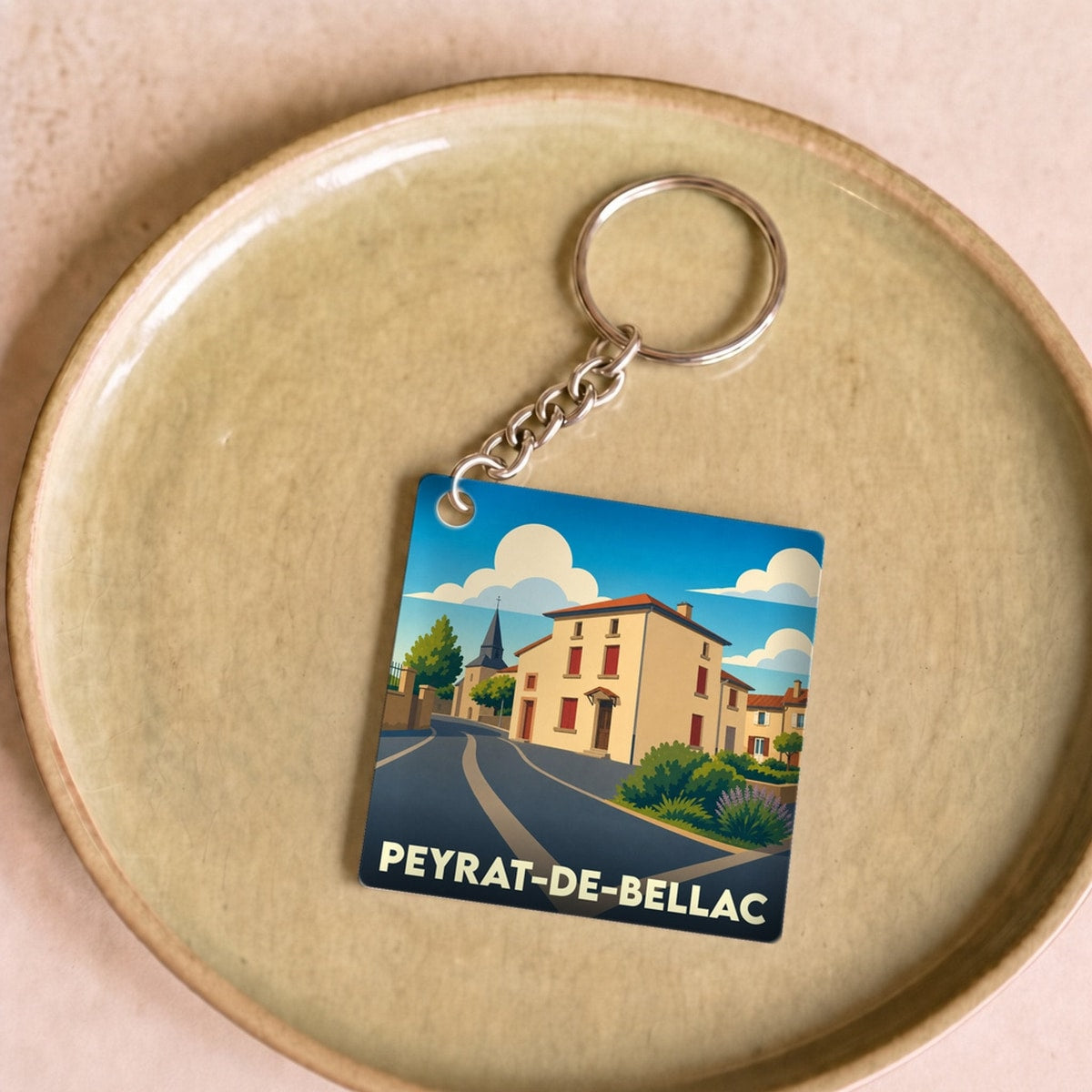 Porte-clés souvenir de la ville de Peyrat-de-Bellac avec une illustration stylisée.