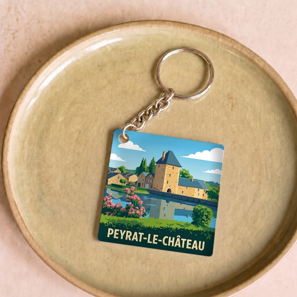 Porte-clés souvenir de la ville de Peyrat-le-Château avec une illustration stylisée.