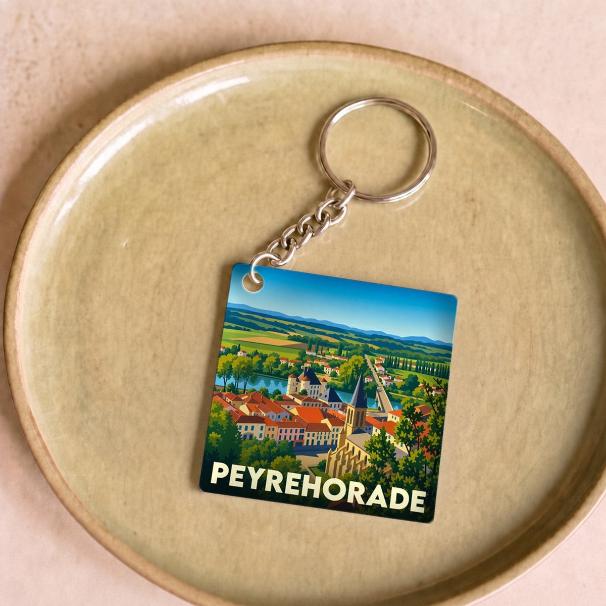 Porte-clés souvenir de la ville de Peyrehorade avec une illustration colorée et stylisée de son paysage.