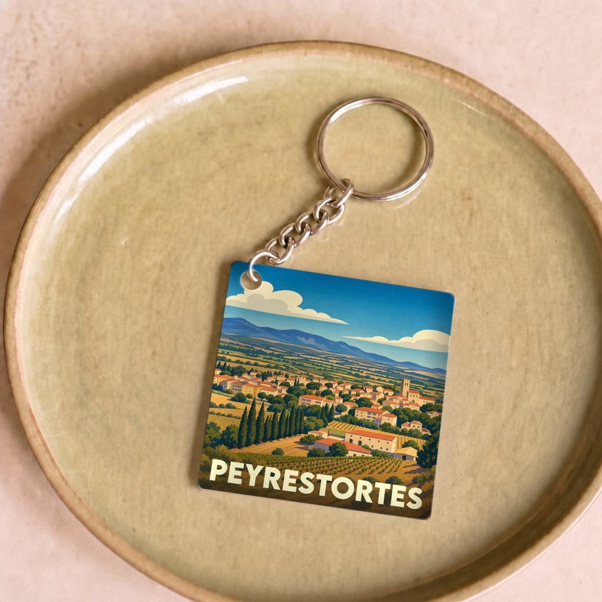 Porte-clés souvenir de la ville de Peyrestortes avec une illustration stylisée de son paysage vallonné.