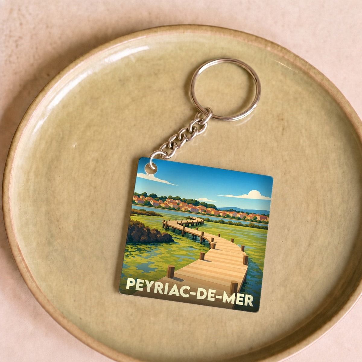 Porte-clés souvenir de la ville de Peyriac-de-Mer avec une illustration stylisée de son célèbre ponton en bois.